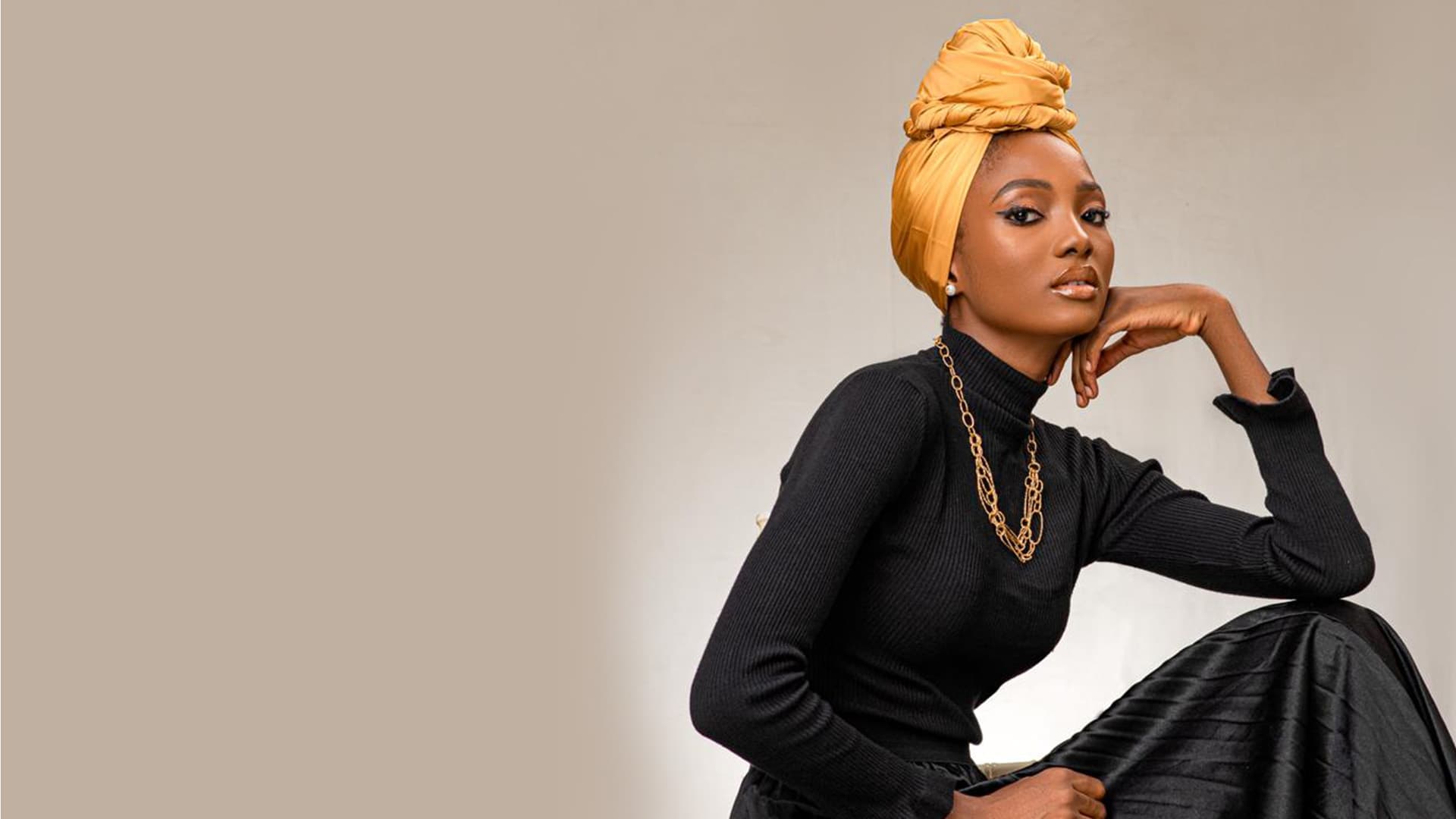 Model in black turtleneck and golden head wrap