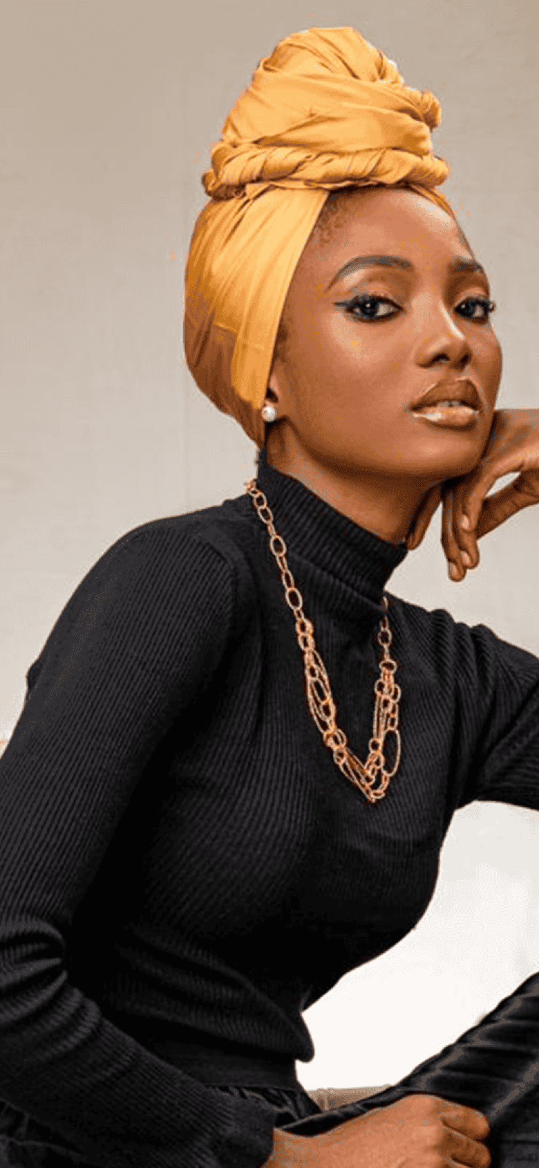Model in black turtleneck and golden head wrap
